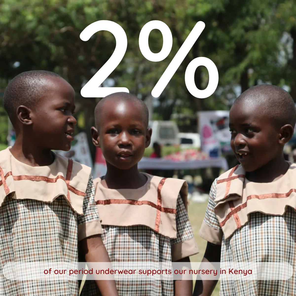 Three children in school uniform in Kenya, with text: 2% of our period underwear supports our nursery in Kenya