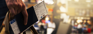 person holding a passport and boarding pass in an airport