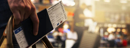 person holding a passport and boarding pass in an airport