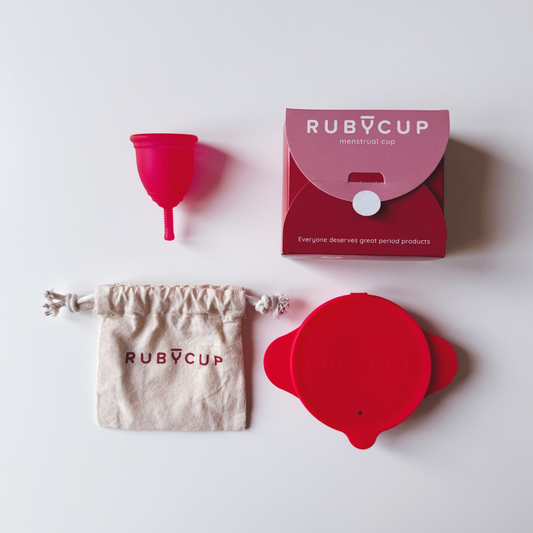 Ruby Cup menstrual product set with red menstrual cup, steriliser, packaging, and cotton pouch