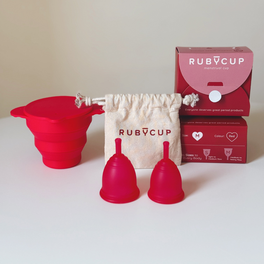 Ruby Cup menstrual cups and steriliser in red with packaging and organic cotton bag on a white background