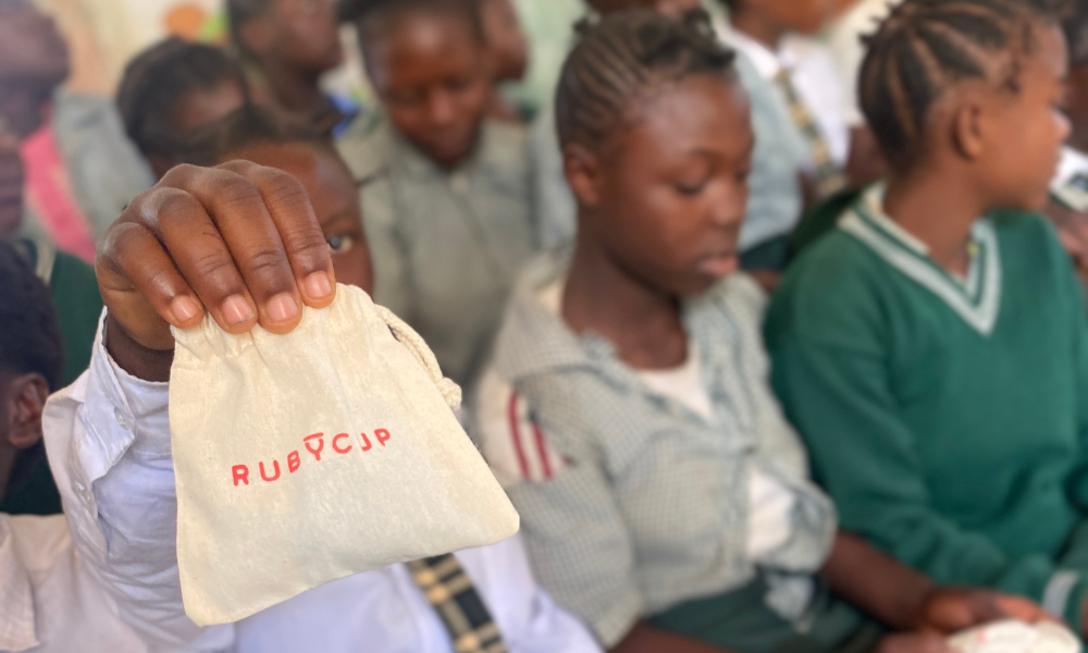 Girl holding a Ruby Cup menstrual cup cotton bag